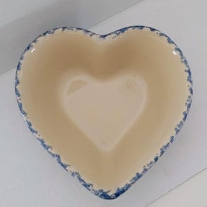 Peut inclure: Un bol en céramique en forme de cœur avec un intérieur crème et un bord bleu. Le bol a une forme de cœur au centre. Le bord présente un motif moucheté et vieilli. Ce bol décoratif est idéal pour servir ou exposer.