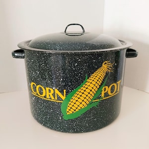 May include: A speckled dark green enamel corn pot with a lid. The pot has a yellow and green corn graphic with the words "CORN POT" in yellow. The pot has two side handles and a handle on the lid.