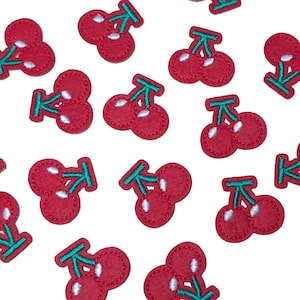 Może przedstawiać: Zbiór czerwonych filcowych łat w kształcie wiśni z zielonymi szypułkami. Wiśnie są rozrzucone na białym tle.