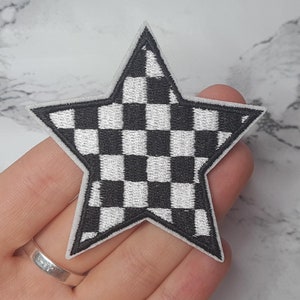 May include: A black and white chequered star-shaped iron-on patch. The patch is made of fabric and has a white outline.