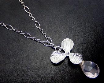 May include: A silver chain necklace with a three-leaf clover pendant and a pink quartz drop.
