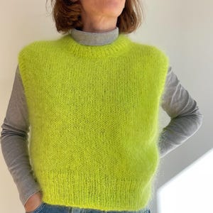 Pode incluir: Um suéter sem mangas de cor verde neon brilhante com uma textura felpuda.