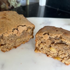 May include: Two slices of banana bread, one cut in half, showing the inside of the bread. The bread is a light brown color and has a slightly crumbly texture.