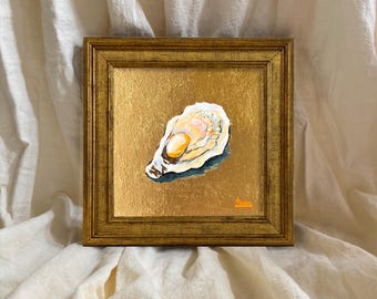 May include: A square painting of an oyster shell centered on a textured gold leaf background, enclosed in a matching ornate gold frame. The oyster features shades of white, cream, and soft orange, with a small orange signature in the corner.