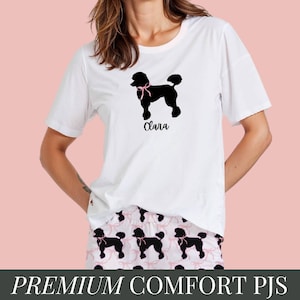 Puede incluir: Camiseta blanca con una silueta negra de un caniche con un lazo rosa y el nombre "Clara" impreso en la parte delantera. Pantalones de pijama a juego con un patrón repetido de caniches negros con lazos rosas sobre un fondo blanco.