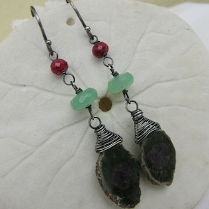 May include: A pair of silver earrings with green and red gemstone beads and a large green agate stone wrapped in silver wire.