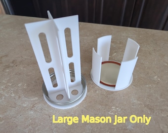 May include: White plastic jar lid holder for large mason jars. The holder has a circular base and four vertical dividers. The text "Large Mason Jar Only" is printed below the holder.