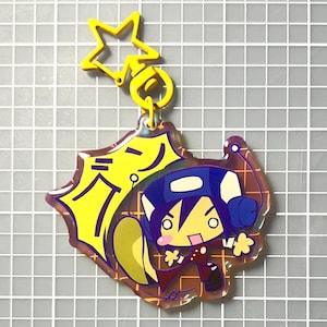 Può includere: Un portachiavi a forma di stella gialla attaccato a un ciondolo in acrilico trasparente. Il ciondolo presenta un personaggio dei cartoni animati con i capelli blu e un abito rosso, su uno sfondo giallo con testo giapponese.