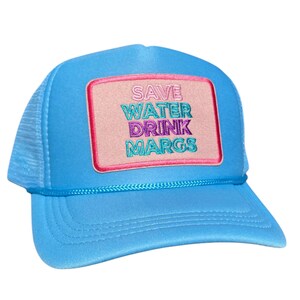 May include: A light blue trucker hat with a pink, white, and blue embroidered patch that says "SAVE WATER DRINK MARGS".