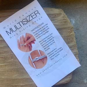 Peut inclure: Une feuille d'instructions blanche pour un outil de mesure de taille de bague appelé "Multisizer". La feuille montre une main démontrant comment utiliser l'outil pour mesurer la taille de la bague. Le texte sur la feuille indique "World Famous Multisizer Ring Sizing Gauge" et "Instructions".