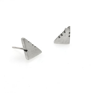 May include: A pair of silver triangle stud earrings with a textured surface.