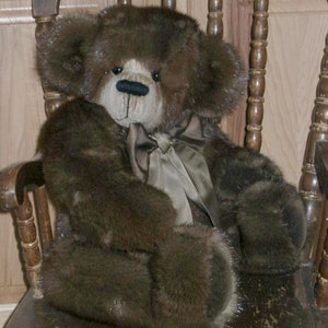 May include: A brown teddy bear with a light brown face and a light brown bow tie is sitting in a wooden rocking chair.