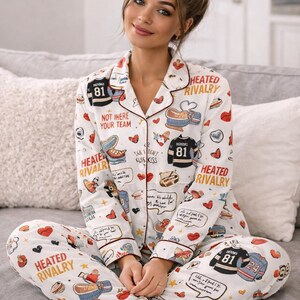 May include: White pajama set with a repeating pattern of hockey jerseys, hearts, and text. The long-sleeved top and pants feature red trim and the words "HEATED RIVALRY" and "NOT HERE YOUR TEAM".