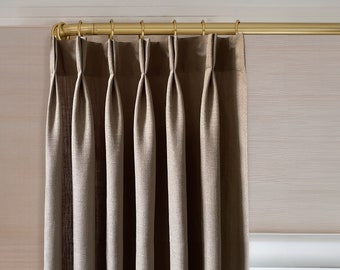 May include: A set of brown curtains with pleats hanging from a gold curtain rod.