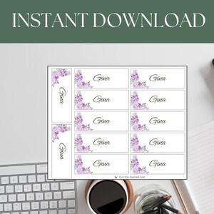 Könnte beinhalten: Druckbare Platzkarte mit einem floralen Design mit lila Blumen und grünen Blättern. Die Karten haben den Namen "Gina" darauf gedruckt. Der Text "Schneiden Sie die gestrichelte Linie" ist ebenfalls enthalten.