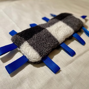 May include: A black and white checked dog toy with blue fabric straps. The toy is made of soft, plush fabric.