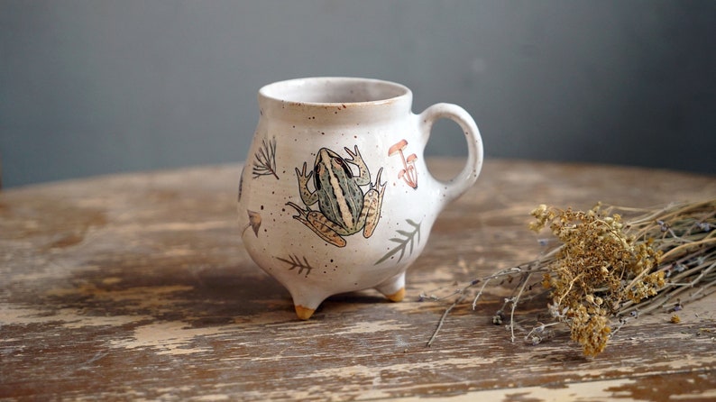 This pottery witches cauldron mug features a vintage picture of a funny frog. Overglaze paint.