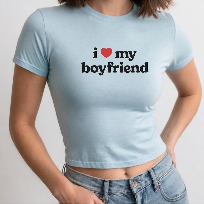 May include: A light blue cropped t-shirt with the text "i &hearts; my boyfriend" printed in black.