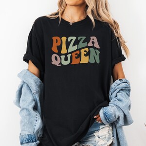 May include: Black t-shirt with the text "Pizza Queen" in colorful retro font.