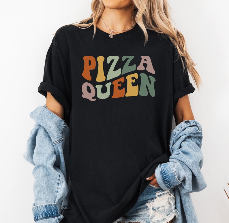 May include: Black t-shirt with the text "Pizza Queen" in colorful retro font.