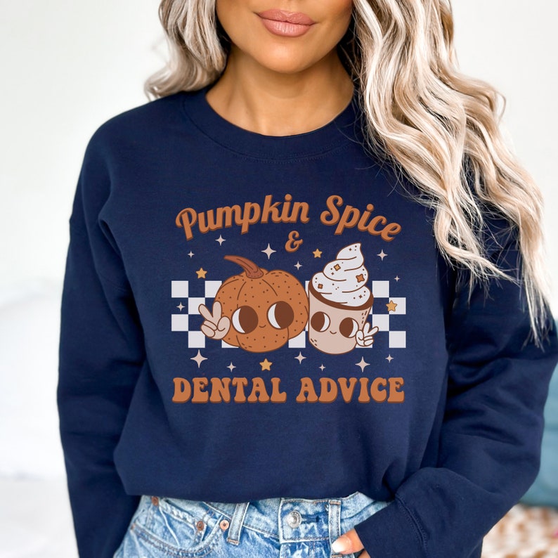 May include: A navy blue sweatshirt with a graphic of a pumpkin and a coffee cup with the text "Pumpkin Spice & Dental Advice".