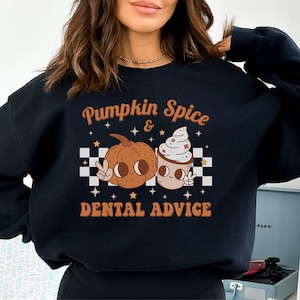 May include: Black sweatshirt with a graphic design featuring a pumpkin and a cup of coffee with the text "Pumpkin Spice & Dental Advice".
