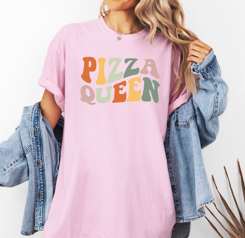 May include: A pink t-shirt with the text "PIZZA QUEEN" in colorful retro-style lettering.
