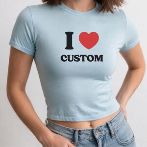 May include: A light blue cropped t-shirt with a black graphic that says "I love custom" with a red heart.
