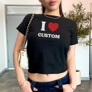 May include: A black cropped t-shirt with a white graphic that says "I love custom" with a red heart in place of the "O".