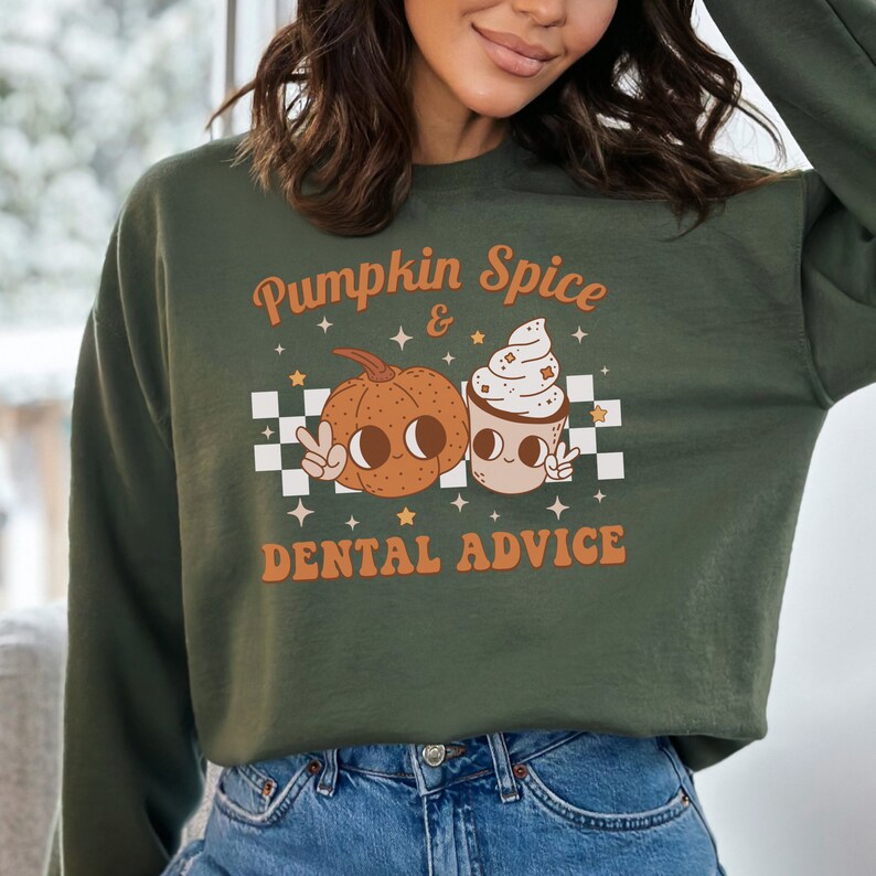May include: Green sweatshirt with a pumpkin spice and dental advice graphic. The graphic features a cartoon pumpkin and a cup of coffee with whipped cream, both with smiling faces and peace signs.