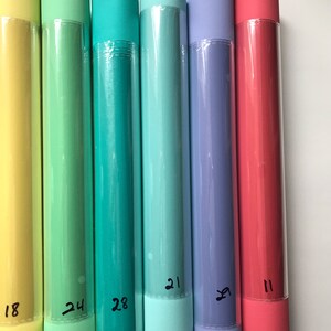 May include: Six rolls of colorful paper, each with a number written on the end. The colors are yellow, green, teal, light blue, purple, and pink.