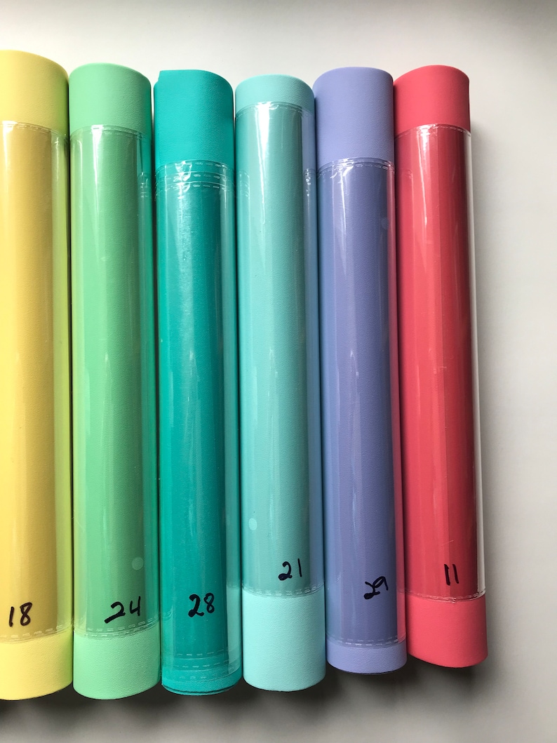 May include: Six rolls of colorful paper, each with a number written on the end. The colors are yellow, green, teal, light blue, purple, and pink.