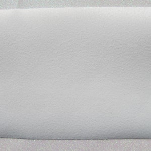 May include: A white sheet of faux fur fabric with a soft, fuzzy texture.