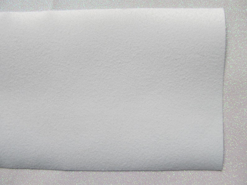 May include: A white sheet of faux fur fabric with a soft, fuzzy texture.