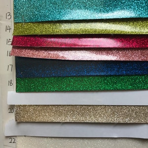 May include: A sample card with numbered swatches of glitter paper in various colors, including teal, yellow, red, pink, black, green, gold, and white.