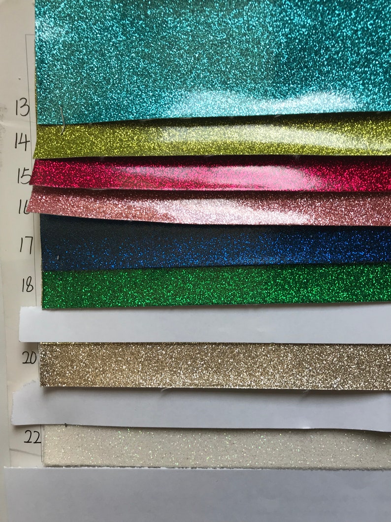 May include: A sample card with numbered swatches of glitter paper in various colors, including teal, yellow, red, pink, black, green, gold, and white.