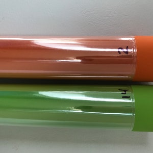 May include: Two rolls of clear, glossy vinyl wrap. The top roll is orange and labeled "2". The bottom roll is green and labeled "1".