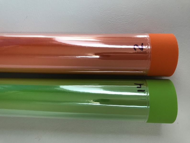 May include: Two rolls of clear, glossy vinyl wrap. The top roll is orange and labeled "2". The bottom roll is green and labeled "1".