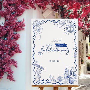 Puede incluir: Un letrero blanco sobre un caballete de madera con dibujos lineales azules y el texto "Welcome to Gracie's bachelorette party". El letrero está decorado con ilustraciones de conchas marinas, bolas de discoteca y temática playera. Flores rosas en el fondo.