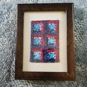 Miniature log cabin quilt, matted and framed