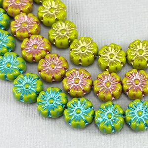 May include: Close-up of flower-shaped beads in various colors. The beads are arranged in rows, showcasing a mix of yellow, pink, and blue hues. The beads have a glossy finish, and the floral design is clearly visible.