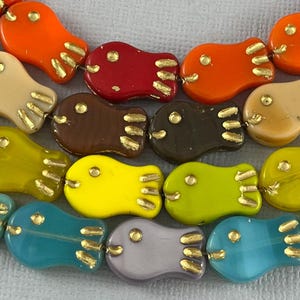 May include: A strand of colorful glass fish beads with gold accents. The beads are in various colors, including orange, red, brown, yellow, green, blue, and purple.