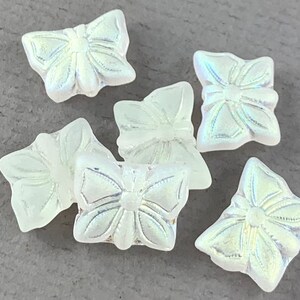 以下が含まれることがあります： 隆起したデザインが施された、虹色の白いガラス製の蝶のビーズが6個あります。