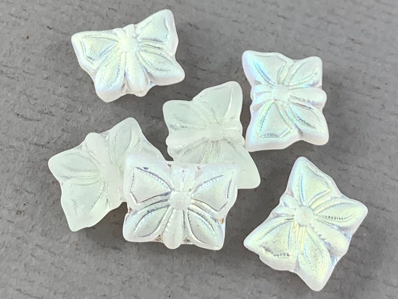 以下が含まれることがあります： 隆起したデザインが施された、虹色の白いガラス製の蝶のビーズが6個あります。
