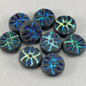 May include: A collection of nine dark gray, round beads. Each bead features a central design with iridescent blue, green, and yellow accents. The beads have a textured surface and a unique, artistic appearance.