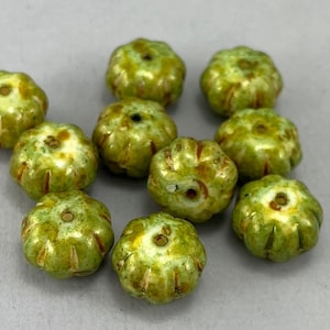 May include: Ten green and white ceramic beads with a textured, bumpy surface. The beads have a glossy finish and are shaped like small pumpkins.