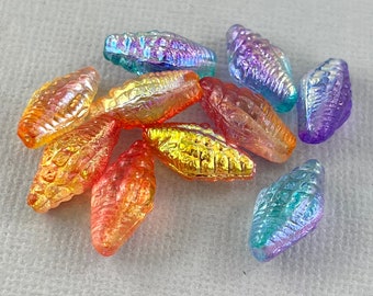 May include: Assortment of iridescent glass beads shaped like seashells in shades of blue, purple, orange, and gold.