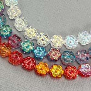 May include: A strand of iridescent flower-shaped glass beads in various colors, including white, red, orange, yellow, blue, and green.