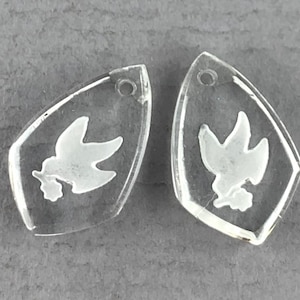 May include: Two clear glass pendants with a white dove design. Each pendant has a hole at the top for hanging.