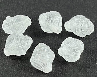 May include: Six clear glass seashells with a textured surface. The seashells are small and have a natural, organic shape.